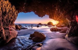 Солнце бьет через скалы на пляже