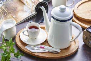 Уютный набор для чаепития: элегантный кофейник, чашка с блюдцем, молочник и набор столовых приборов на деревянном подносе