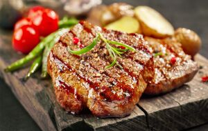 Жареный стейк из говядины с соусом и специями, дополненный зеленым горошком и помидорами черри