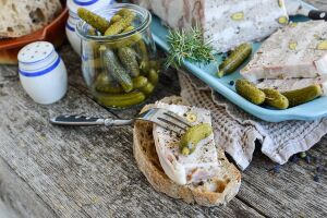 Закусочная тарелка с корнишонами, ломтиками сала и хлебом на деревянной поверхности