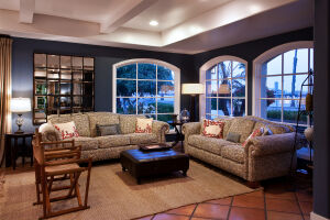 Элегантная гостиная с изысканной мебелью, освещенная торшерами и с видом на ухоженные деревья