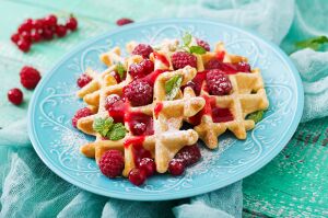 Ароматные вафельки с клубничным соусом и свежей мятой на нежной голубой тарелке