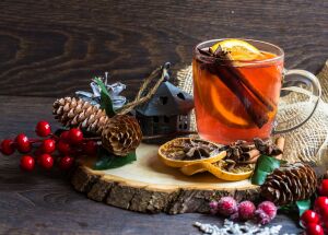 Тёплый зимний напиток с апельсином, корицей и еловыми ветками на деревянном подносе