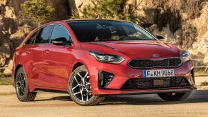 Красный Kia ProCeed GT Line на фоне солнечного пейзажа с зеленью